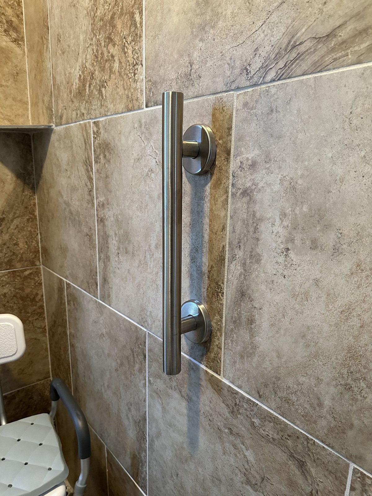 Vertical metal grab bar on a tiled shower wall