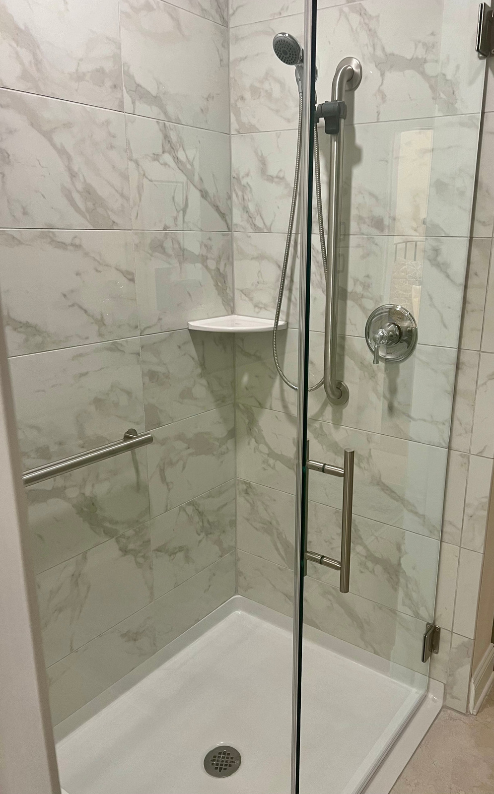 Tiled shower with grab bars and a handheld shower head
